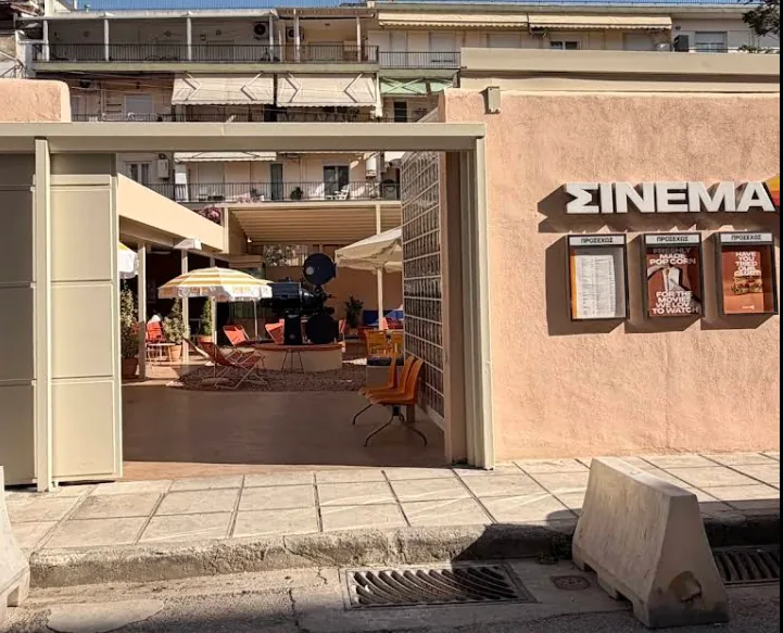 Street-level entrance of Σινεμά with the sign and courtyard visible through the gate