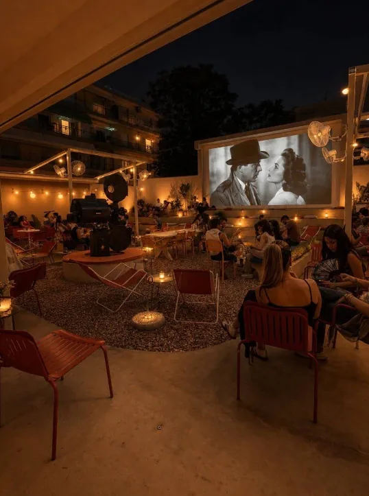 Guests watching an outdoor film screening at night among string lights and candles