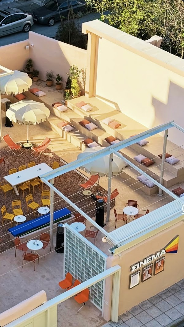 Aerial view of the Σινεμα courtyard with colorful chairs, umbrellas and cushioned steps